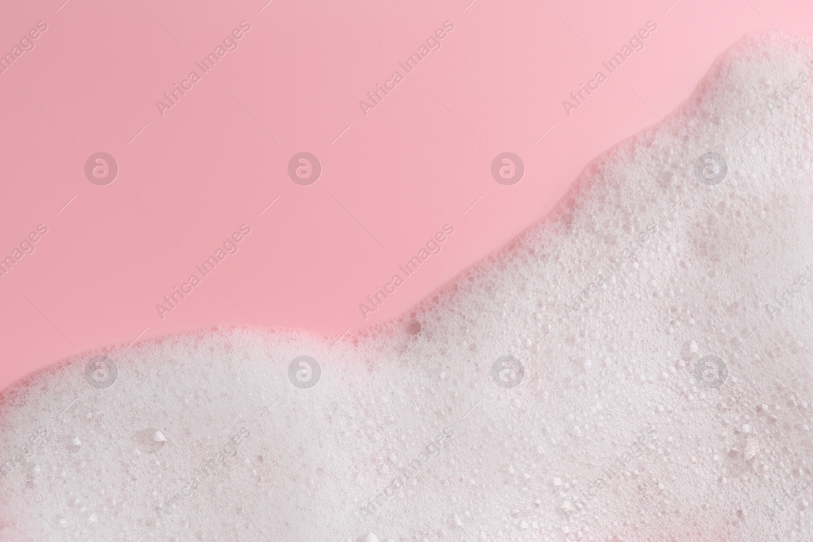 Photo of White fluffy foam on pink background, top view. Space for text