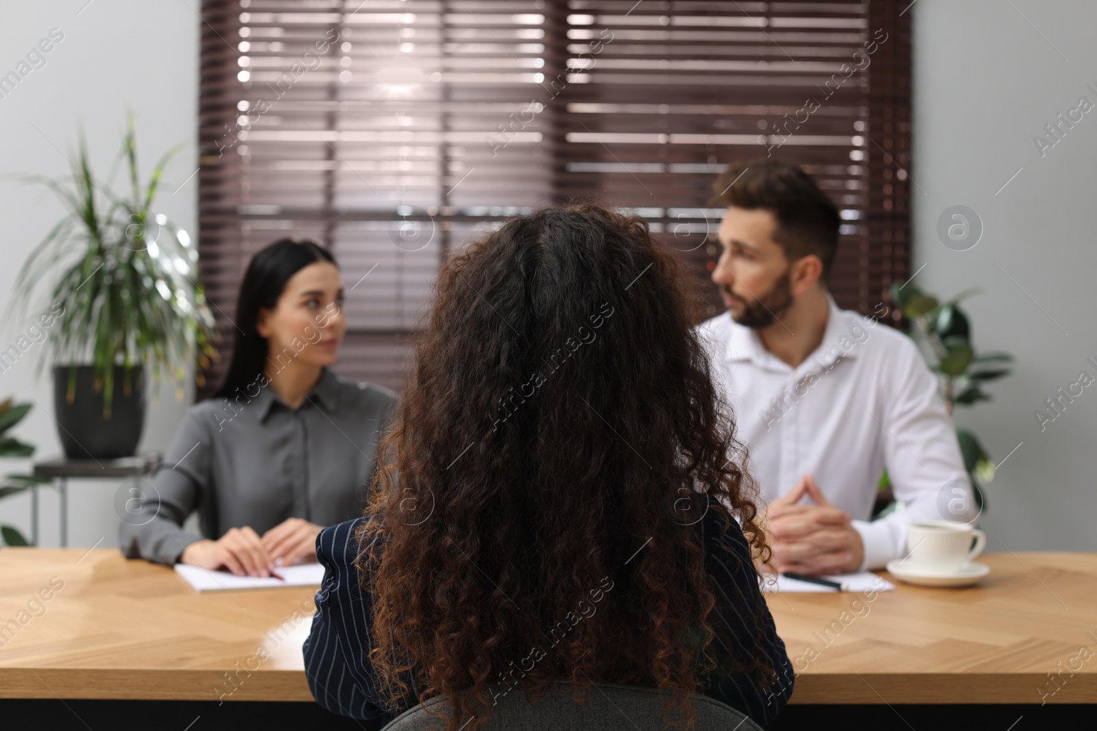 Photo of Coworkers conducting job interview with African American woman in office, back view. Racism concept