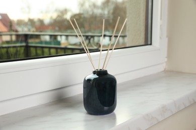 Photo of Aromatic reed air freshener on windowsill indoors