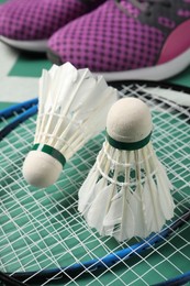 Photo of Feather badminton shuttlecocks, rackets and sneakers on court, closeup