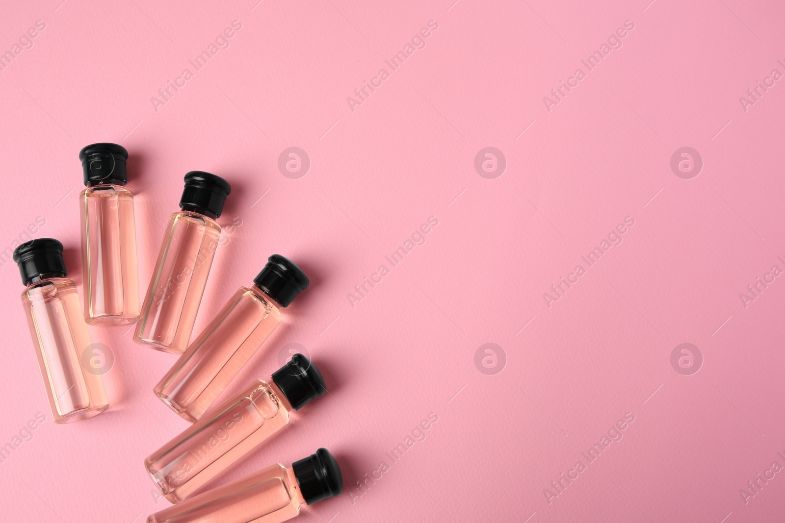 Photo of Bottles of cosmetic products on pink background, flat lay. Space for text