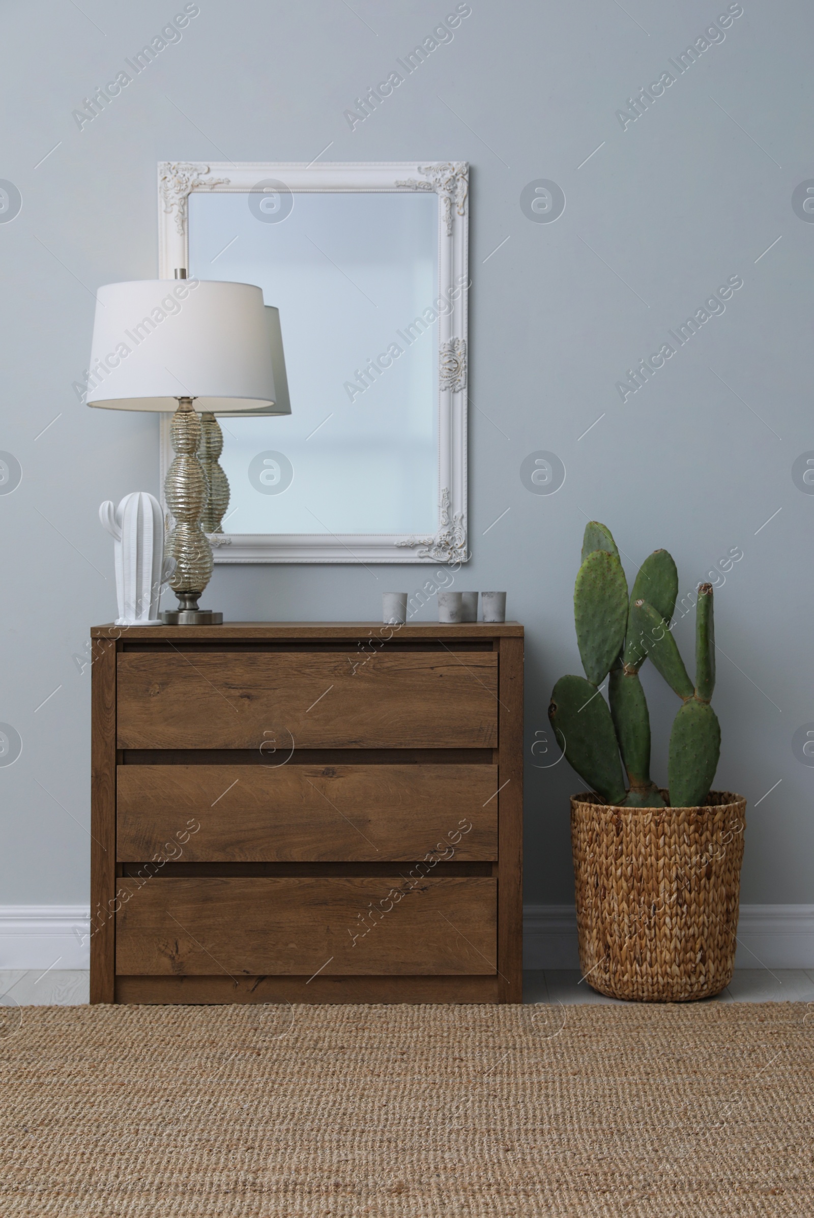 Photo of Light hallway with stylish mirror and chest of drawers. Interior design