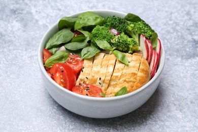 Photo of Healthy meal. Delicious chicken, vegetables and spinach in bowl on light grey table, closeup