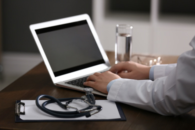 Photo of Professional doctor working on laptop in office, closeup