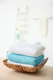 Photo of Wicker tray with towels on table against blurred background