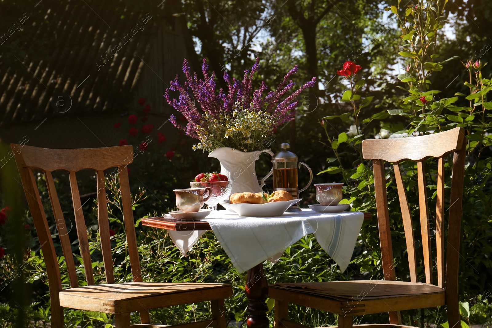 Photo of Beautiful bouquet of wildflowers on table served for tea drinking in garden