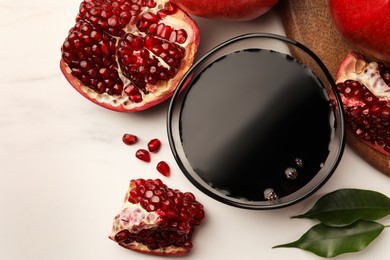 Photo of Glass bowl of tasty pomegranate sauce and fresh ripe fruits on white marble table, flat lay