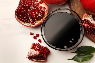 Glass bowl of tasty pomegranate sauce and fresh ripe fruits on white marble table, flat lay