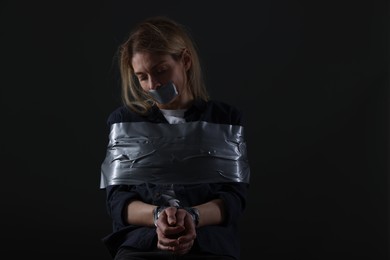 Woman taped up and taken hostage on dark background