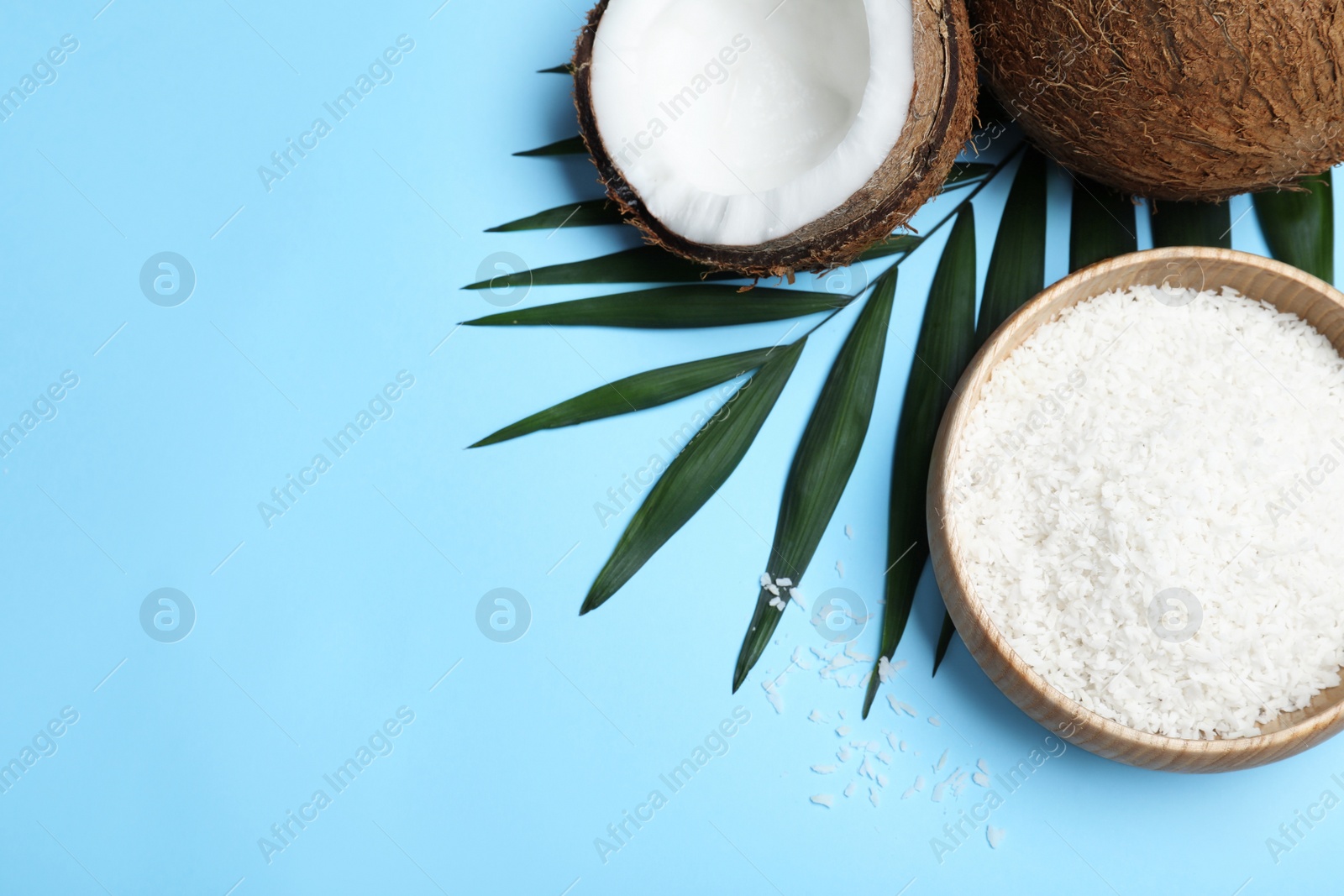 Photo of Flat lay composition with fresh coconut flakes on light blue background. Space for text