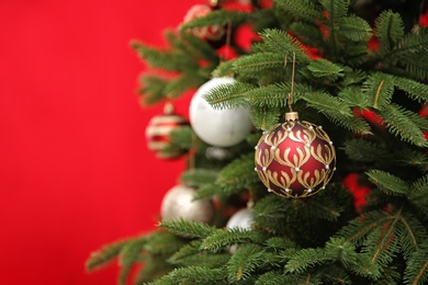 Photo of Beautifully decorated Christmas tree against color background, closeup