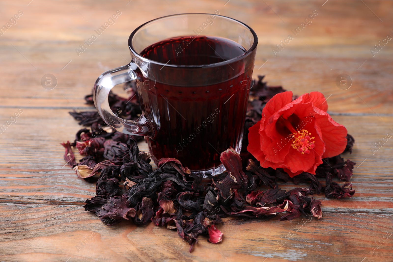 Photo of Delicious hibiscus tea and dry flowers on wooden table