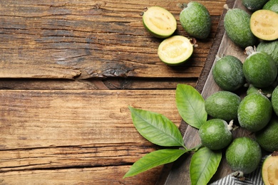 Flat lay composition with fresh green feijoa fruits on wooden table, space for text