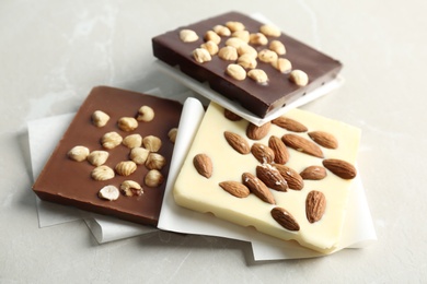 Different chocolate bars with nuts on grey background