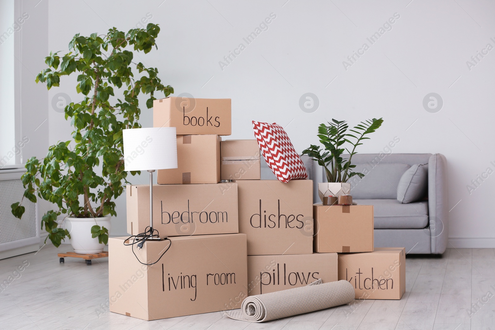 Photo of Pile of moving boxes and household stuff in living room