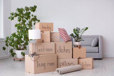 Photo of Pile of moving boxes and household stuff in living room