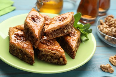 Delicious sweet baklava with walnuts and mint on turquoise wooden table, closeup