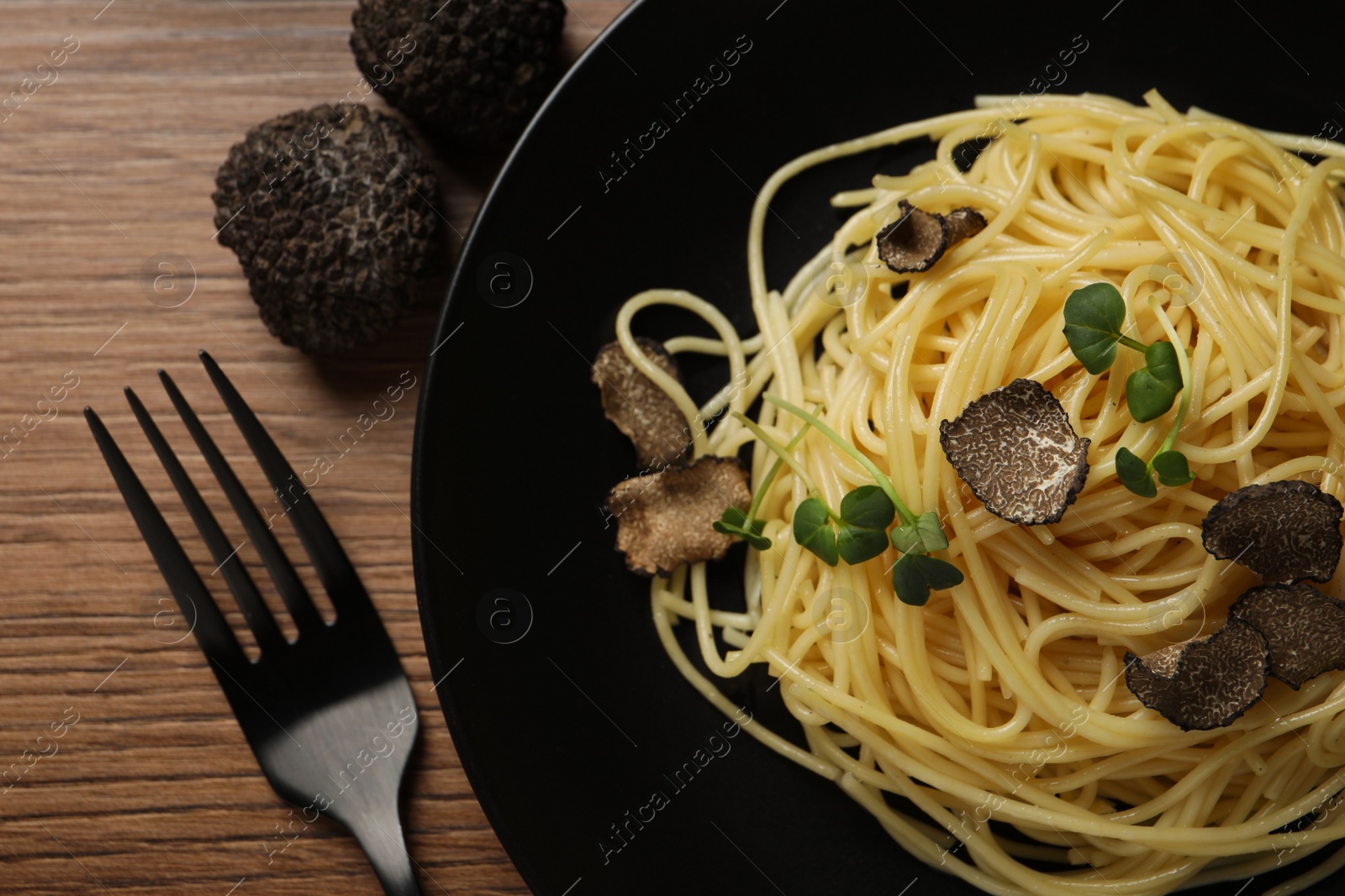 Photo of Tasty spaghetti with truffle on wooden table, flat lay