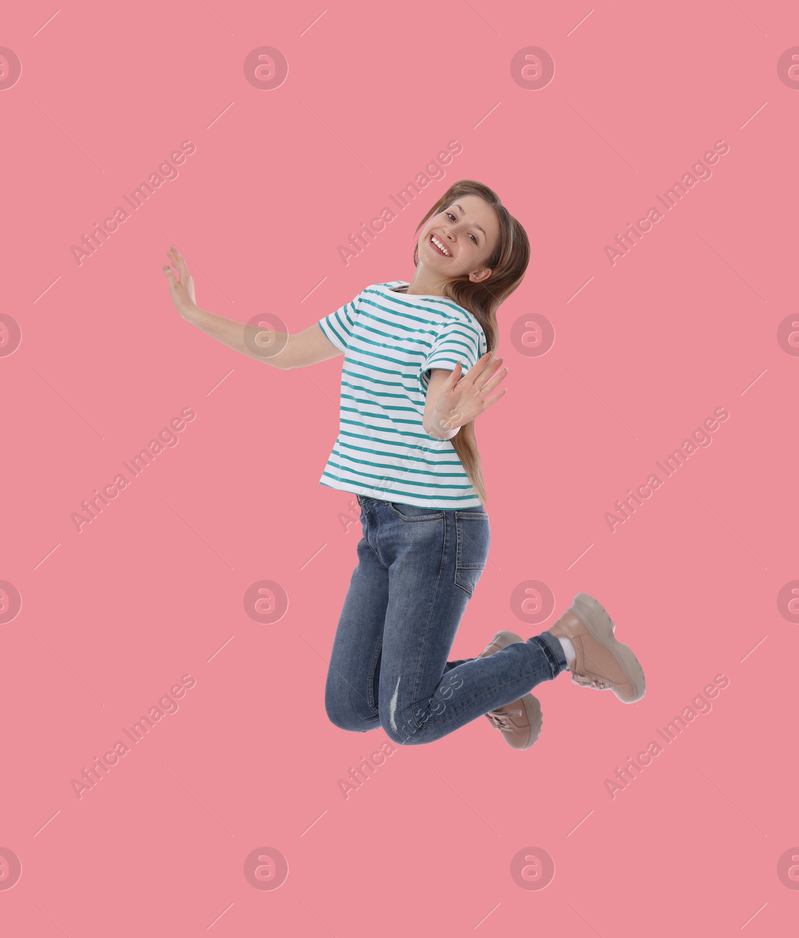 Image of Happy cute girl jumping on dusty pink background