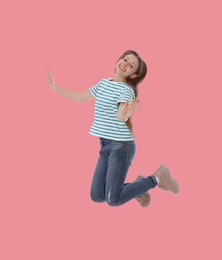 Image of Happy cute girl jumping on dusty pink background