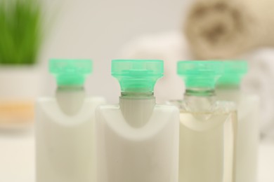 Photo of Mini bottles of cosmetic products on blurred background, closeup