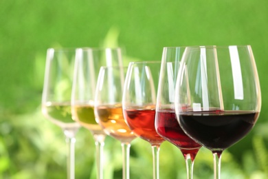 Photo of Row of glasses with different wines against blurred background, closeup
