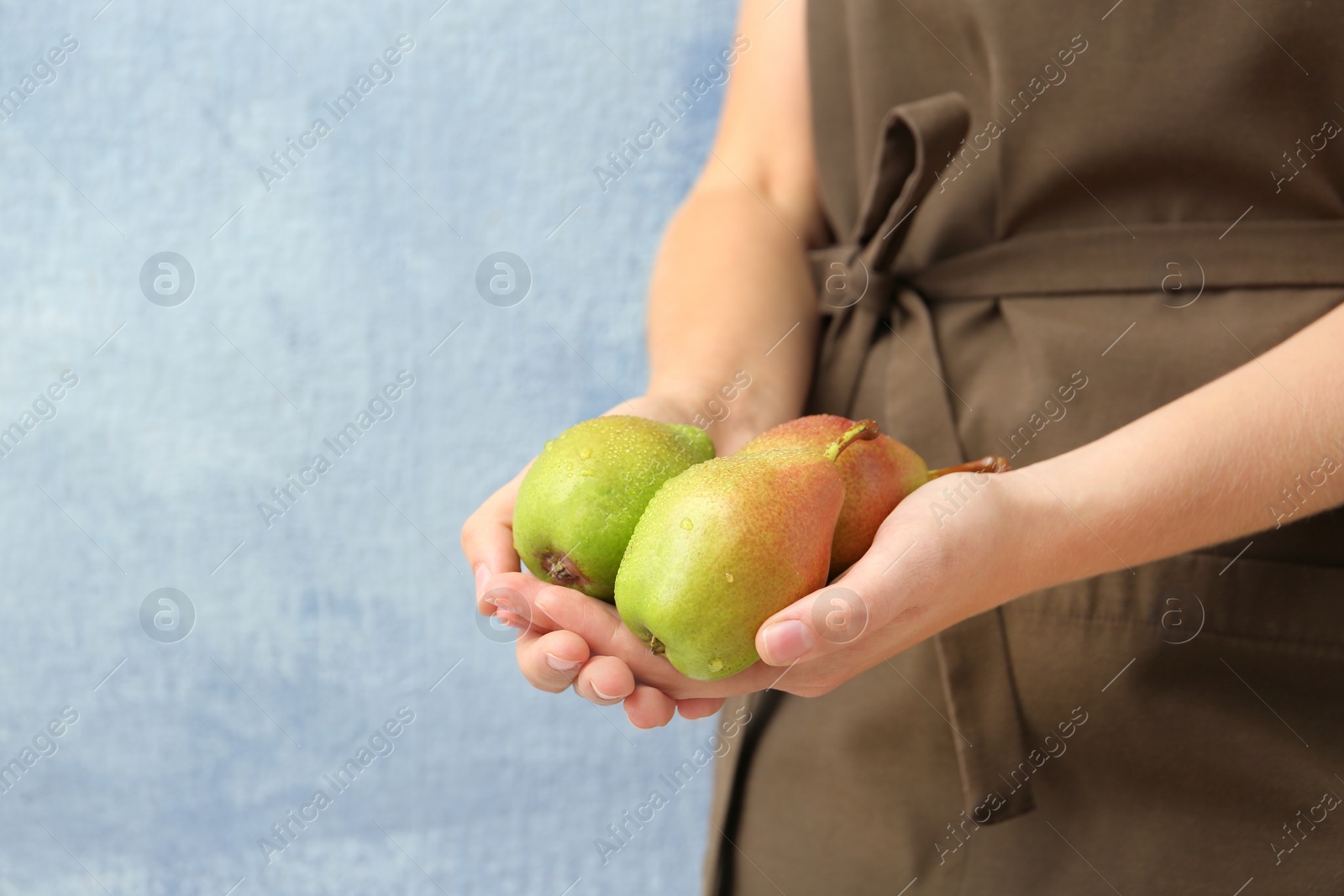 Photo of Woman in apron with ripe pears on color background, closeup. Space for text