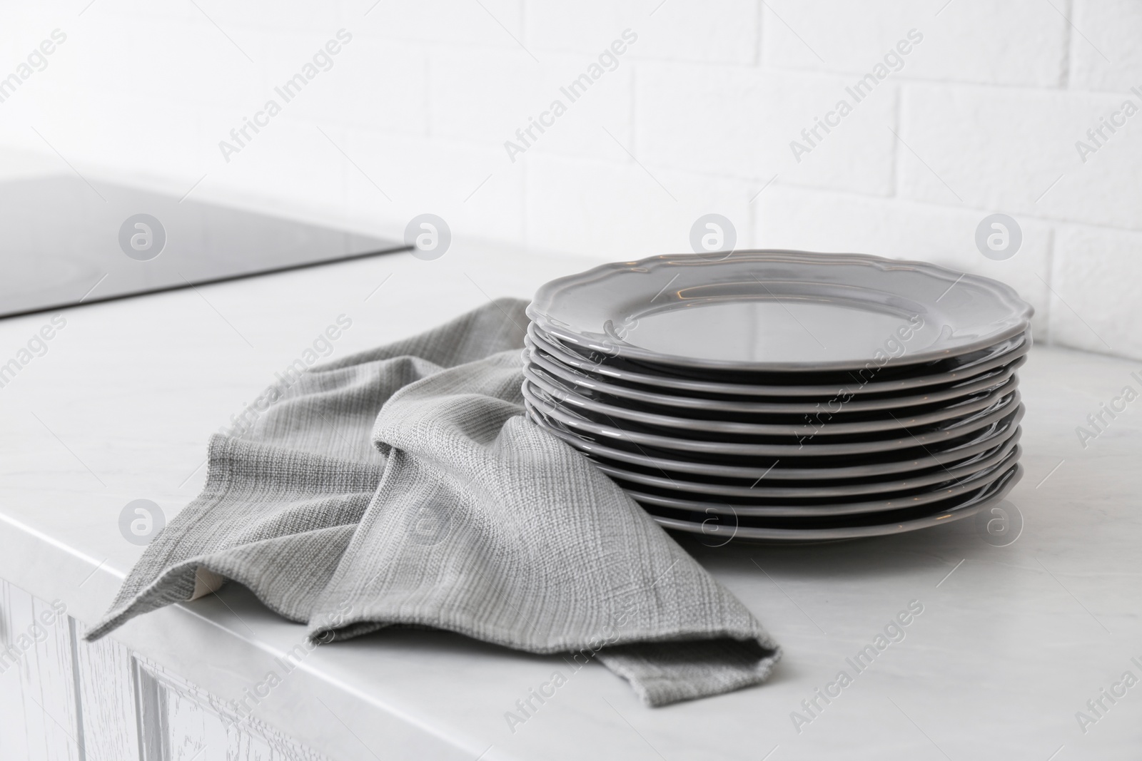 Photo of Clean grey towel and stack of plates on kitchen counter