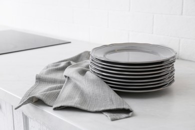 Clean grey towel and stack of plates on kitchen counter