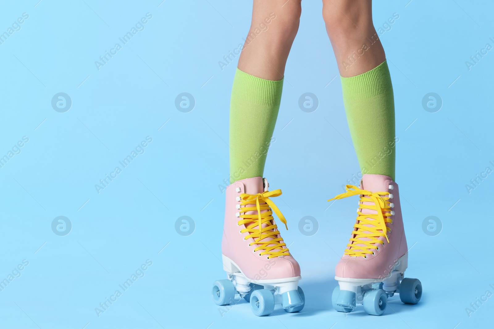 Photo of Woman with vintage roller skates on color background, closeup. Space for text