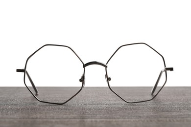 Stylish glasses with metal frame on wooden table against white background