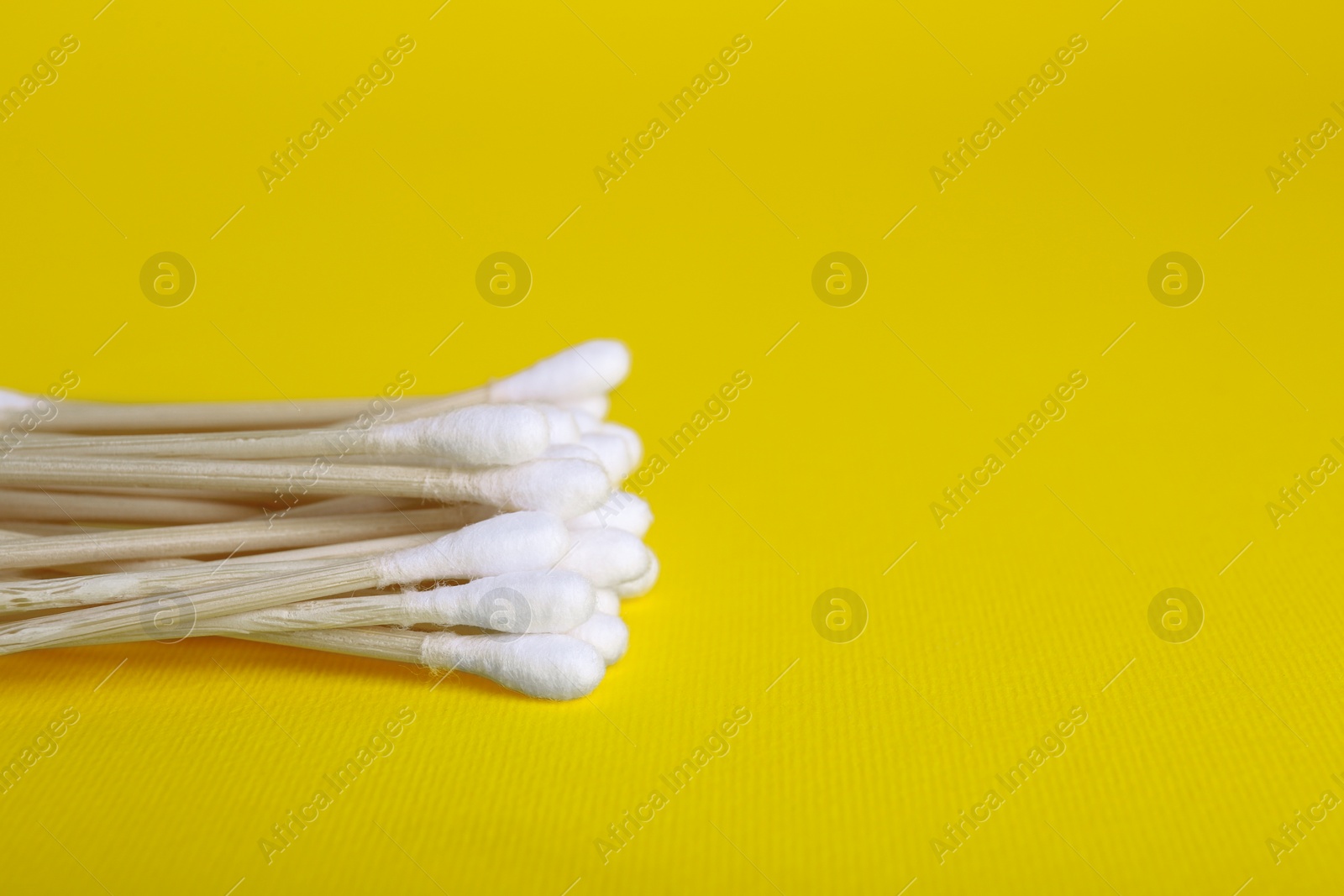 Photo of Wooden cotton buds on yellow background. Space for text