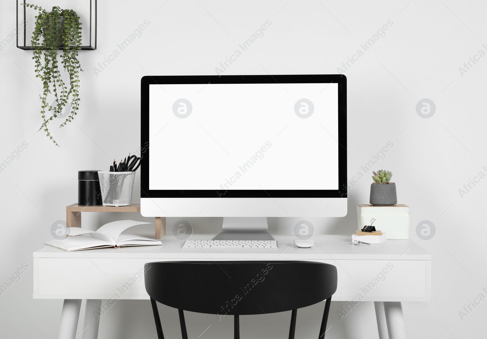 Photo of Cozy workspace with computer, houseplants and stationery on wooden desk at home