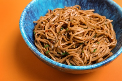 Bowl of buckwheat noodles on color background, closeup