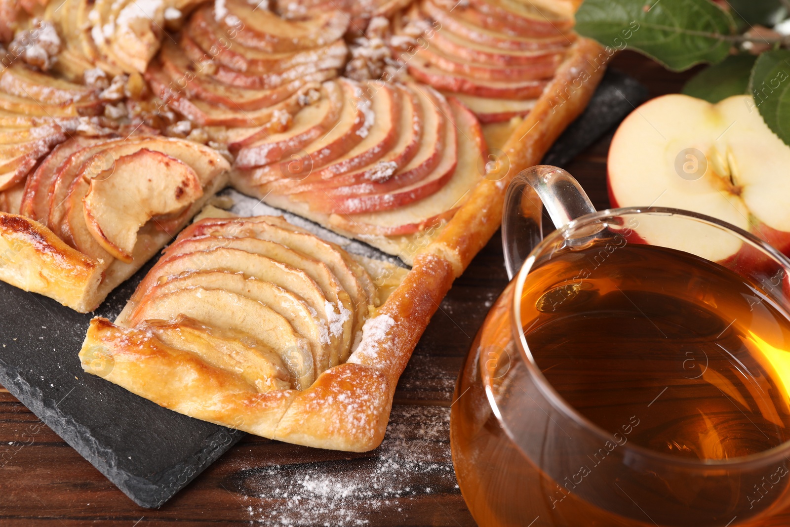 Photo of Freshly baked apple pie served with tea on wooden table, closeup