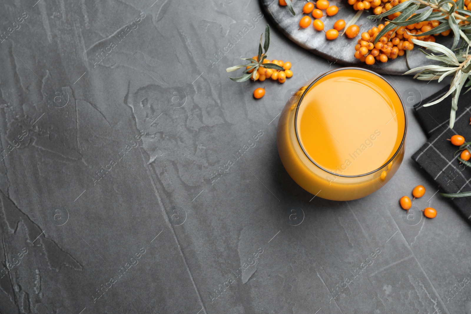 Photo of Sea buckthorn juice and fresh berries on black table, flat lay. Space for text