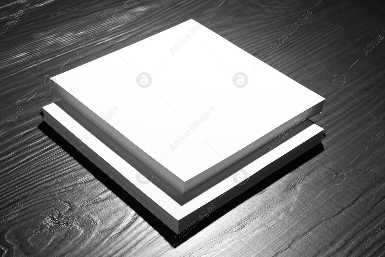 Photo of Stack of blank paper sheets for brochure on black wooden background. Mock up