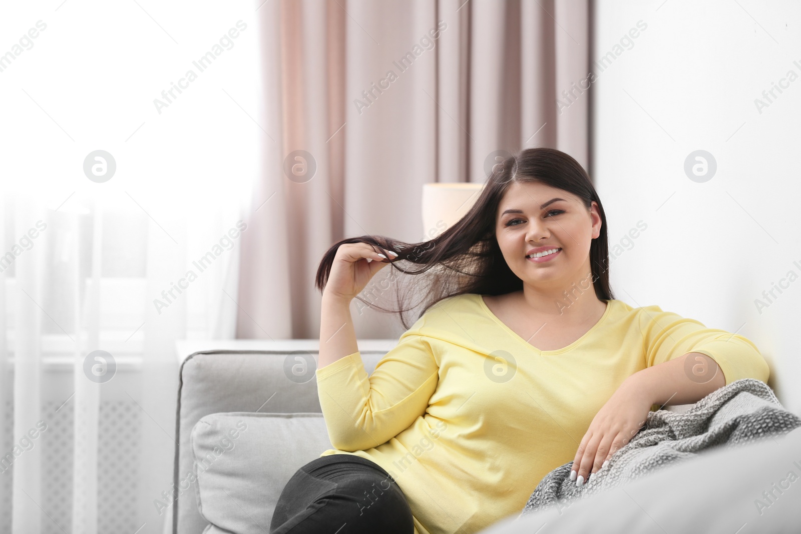 Photo of Beautiful overweight woman on sofa in living room. Plus size model