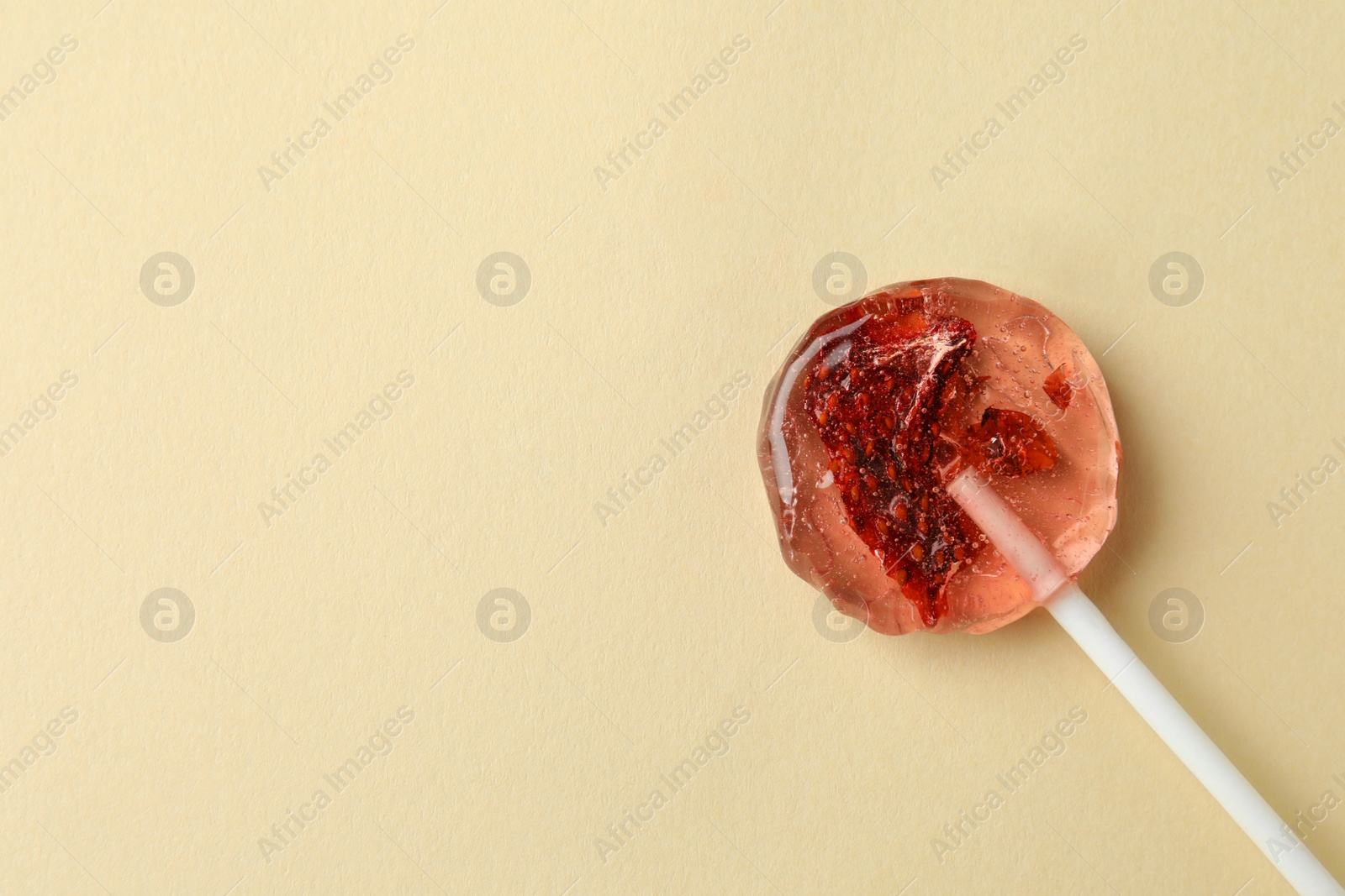Photo of Sweet colorful lollipop with berries on beige background, top view. Space for text