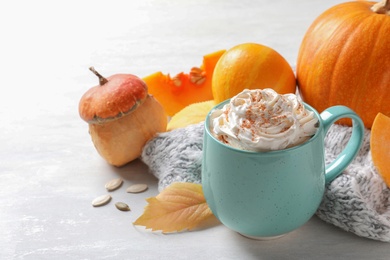 Cup with pumpkin spice latte and  autumn decor on light table