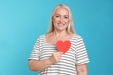 Photo of Portrait of mature woman with decorative paper heart on color background