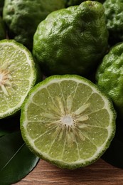 Photo of Fresh ripe bergamot fruits with green leaves on wooden table, closeup