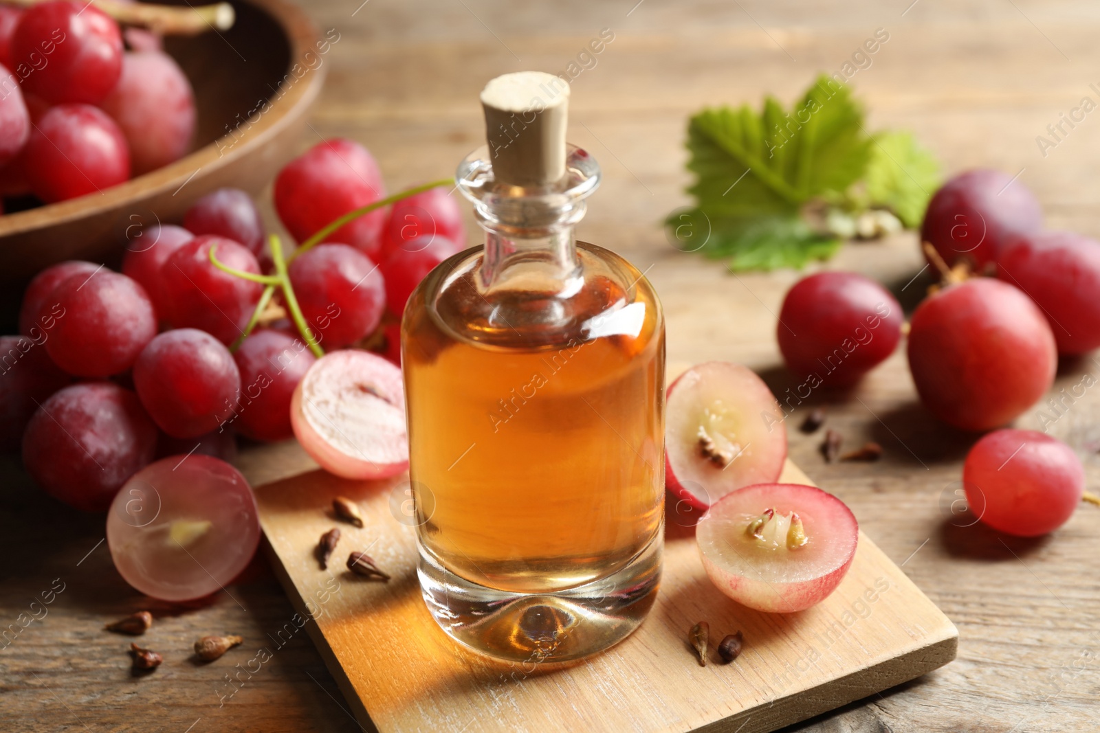 Photo of Bottle of natural grape seed oil on wooden table. Organic cosmetic