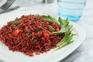 Photo of Tasty brown rice with vegetables on white marble table, closeup