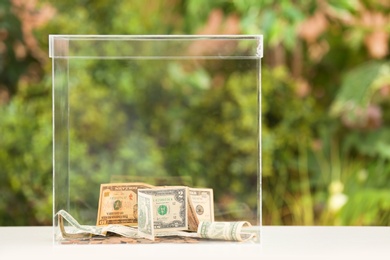 Photo of Donation box with money on table against blurred background