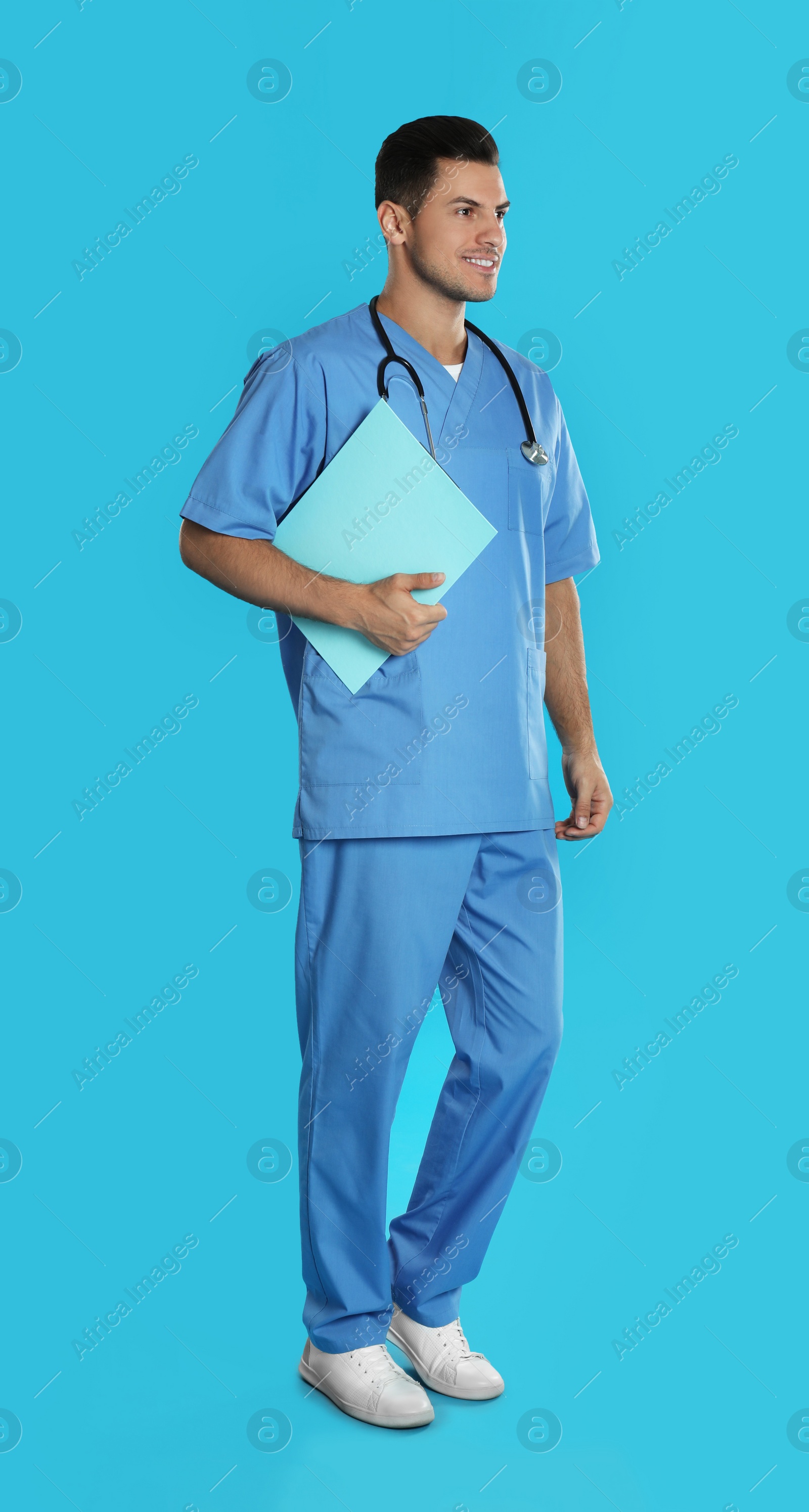 Photo of Handsome doctor with clipboard on blue background