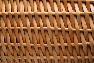 Handmade wicker basket made of natural material as background, closeup view