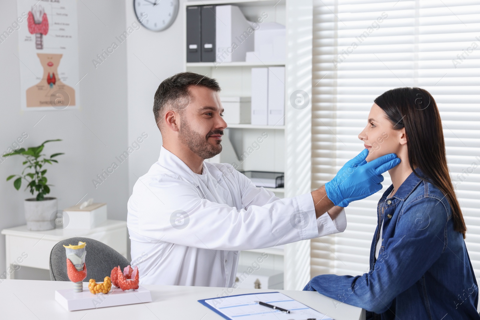 Photo of Endocrinologist examining thyroid gland of patient at table in hospital