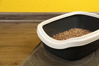 Cat tray with biodegradable litter on floor. Space for text