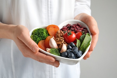 Doctor holding bowl with products for heart-healthy diet, closeup